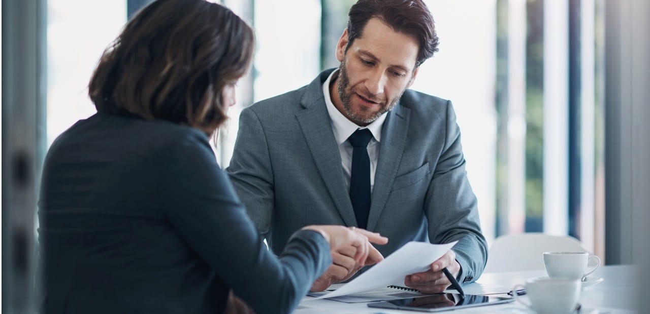Businessman and businesswoman reviewing a document in an office setting.