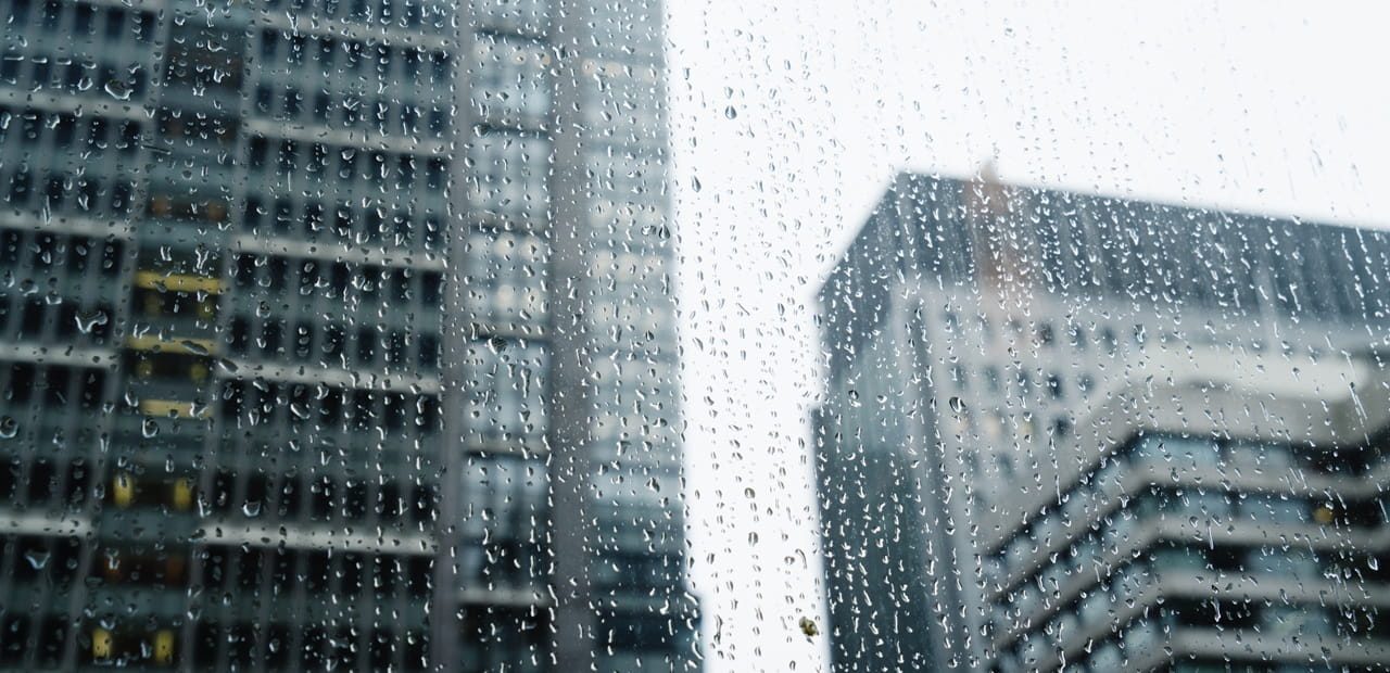 Rain covered window with tall office buildings in the background.